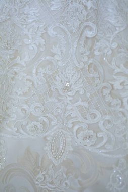Dantelli ve nakışlı, kumaştan gelinliklerle süslenmiş.
