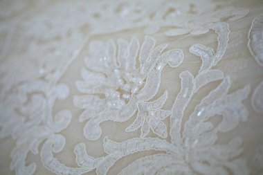 Dantelli ve nakışlı, kumaştan gelinliklerle süslenmiş.