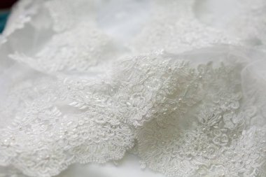 Dantelli ve nakışlı, kumaştan gelinliklerle süslenmiş.