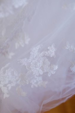 Dantelli ve nakışlı, kumaştan gelinliklerle süslenmiş.