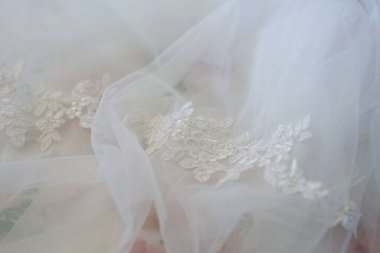 Dantelli ve nakışlı, kumaştan gelinliklerle süslenmiş.