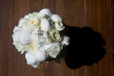 Metalden yapılmış alyanslar bir buket taze çiçeğin üzerinde duruyor. Tatil ve tören kavramı.