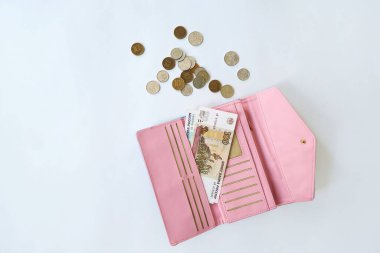 Rus 100 rublelik banknot pembe bir kadının cüzdanında, çeşitli değerlerde paralar etrafa saçılmış. Tasarruf ve tasarruf kavramı, küçük bir miktar finans.