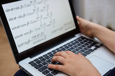 Matematiksel formülü olan bir bilgisayar ekranı ve bir öğrencinin eli. Mesafe ve e-öğrenme, eğitim kavramı.
