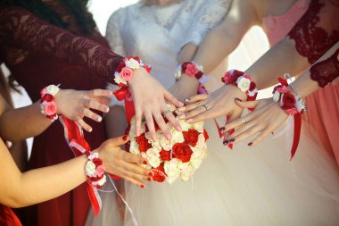 Nedimeler buketin üstünde el ele tutuşuyorlar. Nedimelerin ellerinde parlak renklerde çiçek bilezikleri.