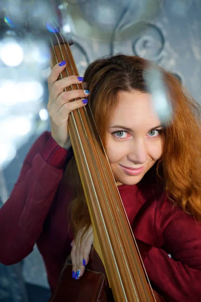 Flickan Den Röda Klänningen Står Studion Och Håller Ett Musikinstrument — Stockfoto