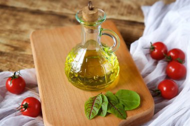 Masanın ahşap yüzeyinde bir şişe taze organik zeytinyağı duruyor. Eski tarz. Yiyecek ve içecek konsepti.