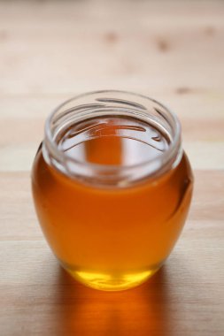 Young light floral honey is poured into a glass jar. Honey color yellow.