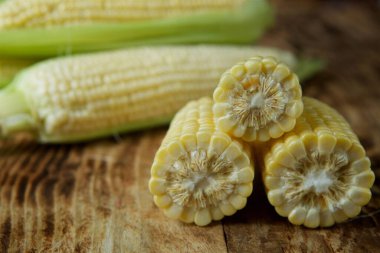 The young cobs of fresh yellow corn on the background of wooden table. Harvest from the organic garden.