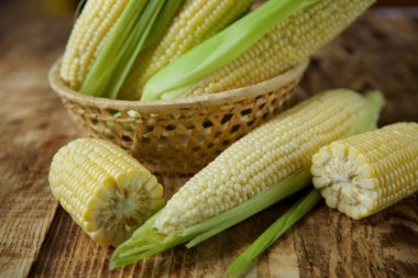 The young cobs of fresh yellow corn on the background of wooden table. Harvest from the organic garden.