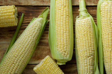 The young cobs of fresh yellow corn on the background of wooden table. Harvest from the organic garden.