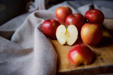 Bright juicy red apples lie on a vintage rustic table. Cut half of the Apple in the foreground.