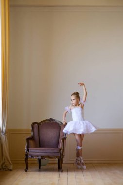 Beyaz etekli küçük kız balerin bale sınıfında yerde yatıyor..