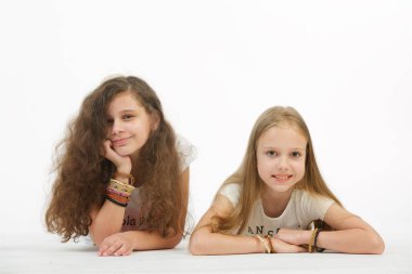 İki genç kız arkadaş izole edilmiş beyaz arka planda yatar ve kameraya bakarlar..