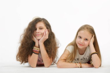 İki genç kız arkadaş izole edilmiş beyaz arka planda yatar ve kameraya bakarlar..