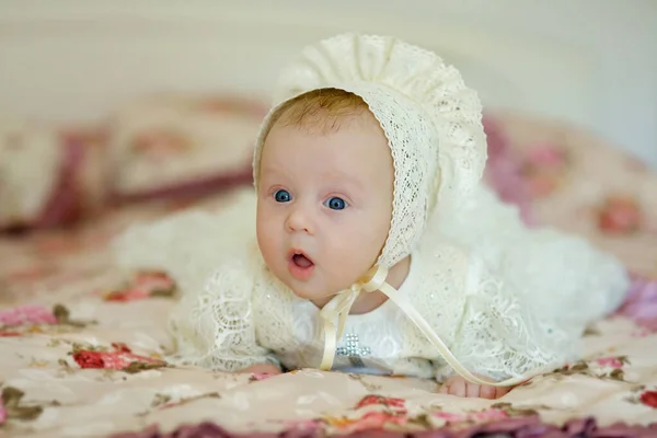 蓝眼睛的小女孩躺在毛毯上 那孩子穿着一件衣服 头戴白色花边的帽子 — 图库照片