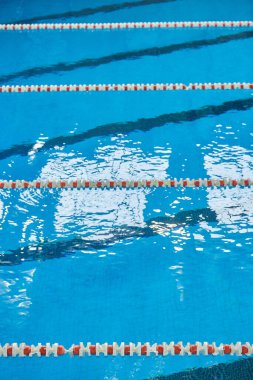 Spor yüzme havuzunda su yüzeyi. Mavi su ve yüzme şeridi ayırıcıları. Spor ve sağlık konsepti.