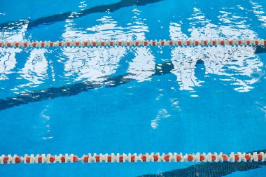 Spor yüzme havuzunda su yüzeyi. Mavi su ve yüzme şeridi ayırıcıları. Spor ve sağlık konsepti.