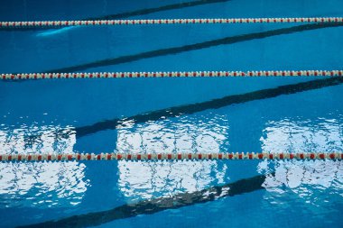 Spor yüzme havuzunda su yüzeyi. Mavi su ve yüzme şeridi ayırıcıları. Spor ve sağlık konsepti.