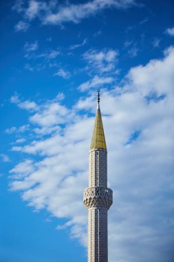 Bulutlu mavi gökyüzüne karşı beyaz taştan yapılmış güzel bir minare. İslam ve Müslüman gelenekleri ve dini. İnanç ve dini binalar kavramı.
