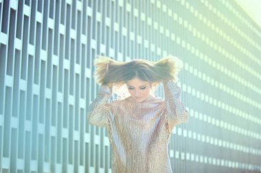 Güzel, modaya uygun giyinmiş bir kız modern binanın etrafında dolanıyor..