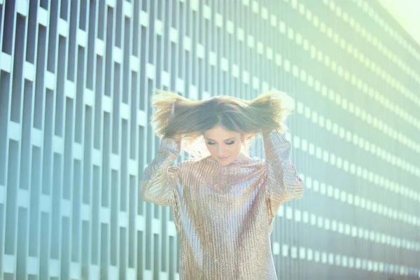 Güzel, modaya uygun giyinmiş bir kız modern binanın etrafında dolanıyor..