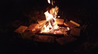 Yakın plan, ateşten alevler. Bir gece yangını, odunlar yanıyor, kıvılcımlar uçuşuyor. 4k