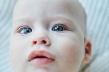 Bir erkek bebek yumuşak bir yüzeyde yatıyor..