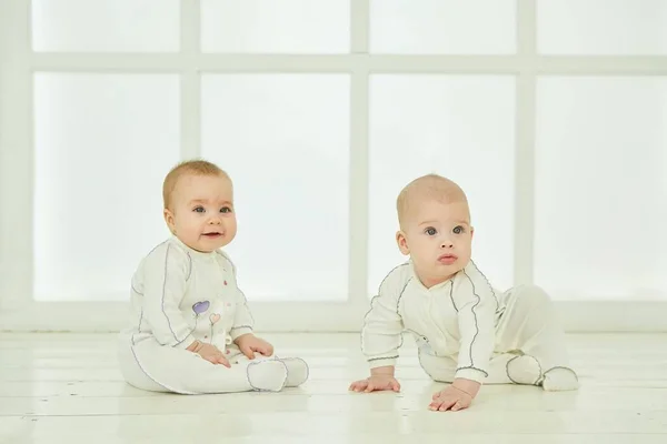 两个小宝宝在一间白色的房间里 童年和母性的概念 — 图库照片