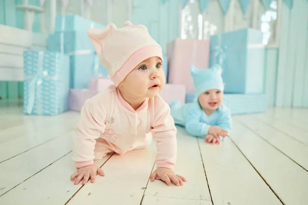 两个孩子躺在明亮的房间里柔软的表面上 穿着蓝色和粉色的衣服 儿童和婴儿保育的概念 — 图库照片