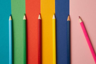 Çeşitli tonlarda çeşitli renkli kalemler her biri kendi renginde, çeşitli tonlarda parlak renkli bir arka planda yatar. Eğitim ve sanatsal yaratıcılık kavramı.
