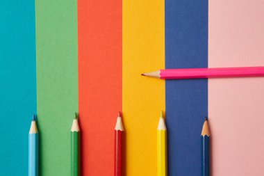 Çeşitli tonlarda çeşitli renkli kalemler her biri kendi renginde, çeşitli tonlarda parlak renkli bir arka planda yatar. Eğitim ve sanatsal yaratıcılık kavramı.