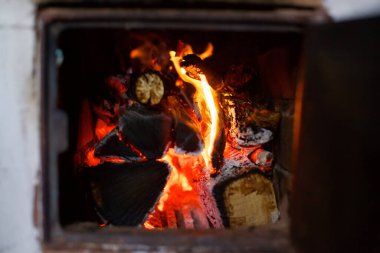Ahşap odunlar bir fırının içinde yatar ve yanar. Kırmızı tuğla fırın. Küllerin ve kömürlerin etrafında.