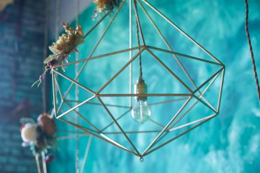 İç dizayn, turkuaz bir duvara karşı sıradan tarzda modern altın renkli metal tel bir avize şeklinde..