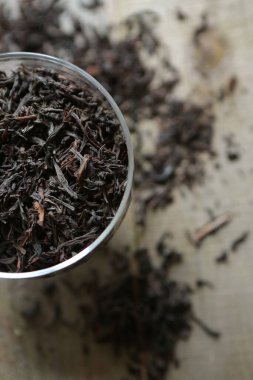 Siyah kuru çay, masanın ahşap yüzeyinde cam bir fincanda yatıyor..