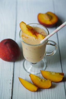 Kokteyl ya da süt içen şeftalili yoğurt cam bir kaseye dökülür ve masanın tahta yüzeyine yerleştirilir. Yiyecek ve içecek kavramı.