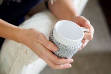 Kadın eli bir bardak içkiyi ellerinde tutuyor. Bir fincan kalın ceketin üzerinde. Yılın bu zamanı soğuk..