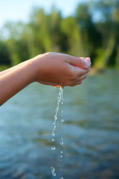 Bir kızın eli ya da bir kızın eli vahşi doğada temiz bir nehri ya da deniz suyunu tutar. Temiz doğal kaynaklar, ekolojik yaşam.