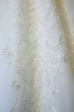 Dantelli ve nakışlı, kumaştan gelinliklerle süslenmiş.