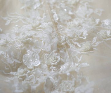 Dantelli ve nakışlı, kumaştan gelinliklerle süslenmiş.