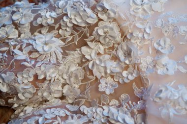 Dantelli ve nakışlı, kumaştan gelinliklerle süslenmiş.