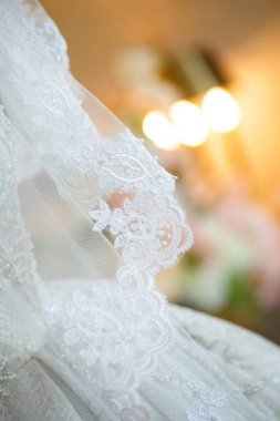 Dantelli ve nakışlı, kumaştan gelinliklerle süslenmiş.