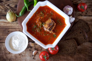 Restorandaki masada biftekli leziz zengin borş var. Arkaplanda siyah ekmek, acı biber, kiraz domates ve sarımsak var. Yemek ve restoran menüsü.