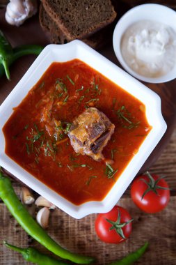 Restorandaki masada biftekli leziz zengin borş var. Arkaplanda siyah ekmek, acı biber, kiraz domates ve sarımsak var. Yemek ve restoran menüsü.