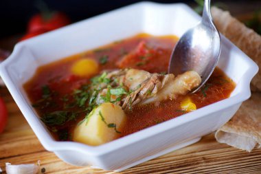 Restorandaki masada etli, patatesli ve sebzeli lezzetli çorba. Ekmek, domates, sarımsak ve fesleğen. Yemek ve restoran menüsü.