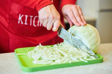 Ham ürün lahanadır, kadın eliyle kesilir. Yemek yapmak için gerekli malzemeler. Mevsimlik sebzeler.