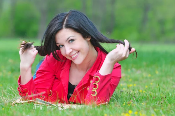 Beautiful young brunette woman reading book on the meadow — Stock Photo, Image