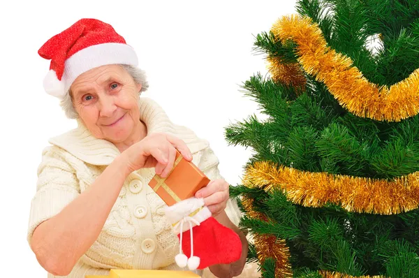 Happy grandma in Santa cap decorating Christmas gifts — Stock Photo, Image