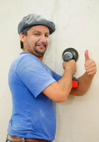 Kézi polírozás a falon, mosolygó építőmunkás Jogdíjmentes Stock Fotók