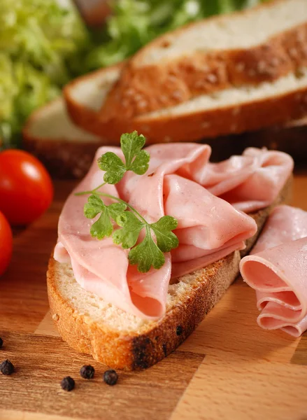 Mortadella in Scheiben geschnitten auf Holzschneidebrett — Stockfoto